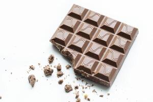 Broken piece of chocolate with crumbs on a white background. Cocoa Dessert photo