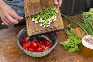 Chop the green onions and tomatoes and place them in a bowl. Prepare the salad. photo