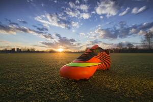 Sports shoes on the background of the field at sunset. Football field with sneakers photo