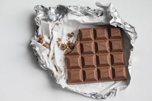 Fragment of chocolate bar in foil close up photo