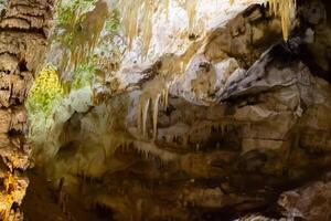 el cueva es karst, increíble ver de estalactitas y estalagnitas iluminado por brillante luz, un hermosa natural atracción en un turista lugar. foto