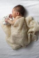 Newborn baby wrapped in a knitted blanket on a light background. photo