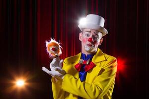 Circus clown performs number. A man in a clown outfit with a toy photo