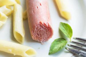 Bitten sausage with pasta with basil leaves on a plate.Half-eaten breakfast photo