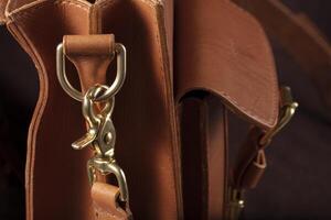 Part of a bag made of brown genuine leather with a metal fastening for the handle. photo