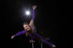 Circus actress performs the number in a beautiful smoke. Manual equilibrium on canes. Flexible girl body.Performance of an air gymnast in a circus photo