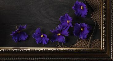 Part of a beautiful frame contains rough weave fabric on a wooden background and violet flowers. Background for the inscription. photo