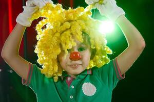 pequeño chico payaso. niño en un payaso peluca con un rojo nariz cerca arriba foto