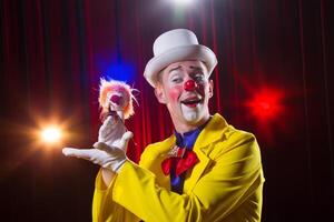 Circus clown performs number. A man in a clown outfit with a toy photo