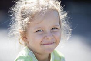 un gracioso niña con un sucio cara mira a el cámara y sonrisas foto