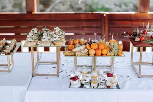 open-air buffet table, sandwiches on skewers before the start of the holiday against the background of flowering trees in the garden photo