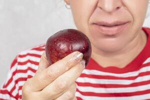 The woman, whose face is not visible, holds a red apple in her hand. photo