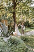 The bride is circling under the groom's hand in a beautiful garden. Bride and groom dancing in the backyard. photo
