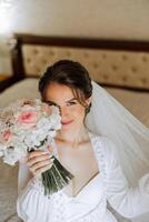 hermosa novia en un vendaje vestido en el Mañana antes de el Boda ceremonia. increíble peinado de el novia. natural y moderno constituir. retrato de un joven novia en un vendaje vestido. foto