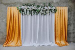 The photo zone at a wedding or birthday celebration is decorated with flowers and illuminated by artificial light