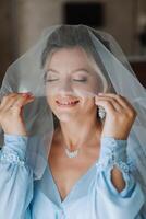 Beautiful bride in a dressing gown in the morning before the wedding ceremony. Incredible hairstyle of the bride. Natural and modern makeup. Portrait of a young bride in a dressing gown. photo