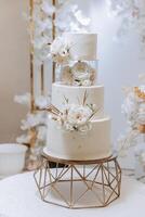 a three-tiered wedding cake decorated with flowers stands on a decorative stand. Decorative wedding cake. Beauty is in the details. photo