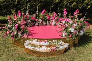 el rosado etapa es decorado con flores en el antecedentes de el bosque. preparación para el Boda ceremonia foto