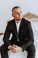 Portrait of a young groom at home before the wedding ceremony. A handsome man dressed in a classic suit. Male portrait. photo
