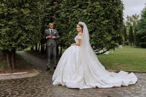 The bride is dressed in an elegant lush white wedding dress with a long veil and is ready for her groom. The first meeting of the bride and groom photo