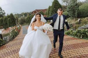 elegante contento novia y novio corriendo en el antecedentes de hermosa naturaleza. boda. hermosa emocional Pareja sonriente y teniendo divertido en el lluvia en un europeo ciudad. foto