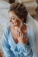 Beautiful bride in a dressing gown in the morning before the wedding ceremony. Incredible hairstyle of the bride. Natural and modern makeup. Portrait of a young bride in a dressing gown. photo