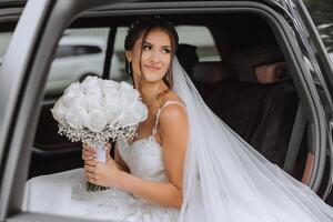 The bride looks out of the car window. Close-up portrait of a pretty shy bride in a car window. Bride smile emotions photo