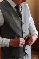 Man fastens the buttons. The groom in a suit. Close up. Man is buttoning his vest. Perfect to the last detail. Modern businessman. photo