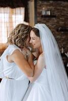 A beautiful and happy mother and her daughter, the bride, are standing next to each other. The best day for parents. Tender moments at the wedding. photo