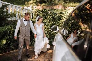 A handsome groom and an elegant bride in a lush white dress are walking in a summer park. Happy bride and groom getting ready for their best day. photo