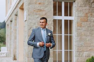 retrato de el novio en naturaleza en el verano. elegante alto novio en un elegante azul negocio traje. empresario en naturaleza. retrato de un exitoso hombre. Boda retrato de el novio. foto