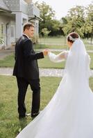 A handsome groom and an elegant bride in a lush white dress are walking in a summer park. Happy bride and groom getting ready for their best day. photo