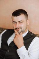 Portrait of a young groom at home before the wedding ceremony. A handsome man dressed in a classic suit. Male portrait. photo