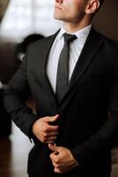 Man fastens the buttons. The groom in a suit. Close up. Man is buttoning his vest. Perfect to the last detail. Modern businessman. photo