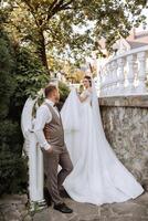 The bride is dressed in an elegant lush white wedding dress with a long veil and is ready for her groom. The first meeting of the bride and groom photo