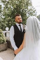 Close-up photo of a wedding couple looking each other in the eyes in nature. The bride and groom look each other in the middle of nature. Tenderness and love in the eyes.