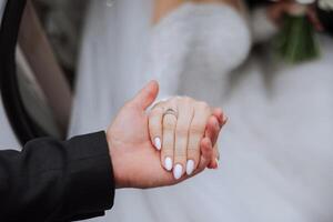 Groom holding bride's hand, cropped photo. Details at the wedding. Gold wedding rings on hands. High quality photo. photo