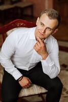 Portrait of a young groom at home before the wedding ceremony. A handsome man dressed in a classic suit. Male portrait. photo