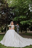 The bride is dressed in an elegant lush white wedding dress with a long veil and is ready for her groom. The first meeting of the bride and groom photo