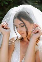 retrato de un hermosa joven novia en un blanco vestir con un largo velo y un maravilloso peinado. sonriente novia. Boda día. maravilloso novia. casamiento. foto