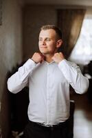 Business shirt. A man in a white shirt fastens the buttons. Young politician, male style, businessman buttoning shirt, male hands close-up, american, european businessman photo