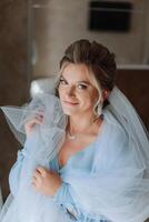 Beautiful bride in a dressing gown in the morning before the wedding ceremony. Incredible hairstyle of the bride. Natural and modern makeup. Portrait of a young bride in a dressing gown. photo