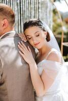 el novia y novio abarcar. el novia suavemente abrazos el novio por el espalda. hermosa Boda Pareja. el concepto de romance en un recién casados relación. Luna de miel. foto