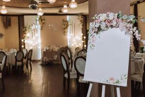 un original floral decorado tablero con un blanco hoja, en contra el fondo de un abandonado Boda salón en el antecedentes. con un inscripción lámina. foto