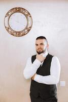 Portrait of a young groom at home before the wedding ceremony. A handsome man dressed in a classic suit. Male portrait. photo