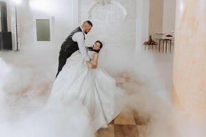 Wedding dance of the bride and groom. The first dance of the bride and groom in an elegant wedding hall with the use of heavy smoke and pyrotechnic lights, confetti. photo