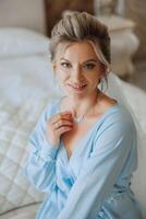 Beautiful bride in a dressing gown in the morning before the wedding ceremony. Incredible hairstyle of the bride. Natural and modern makeup. Portrait of a young bride in a dressing gown. photo