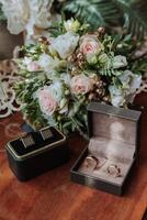 On the floor are men's dark leather shoes and a black belt, a man's suit on a mannequin, a wedding bouquet of flowers, wedding rings, men's perfume. Photo, top view. photo