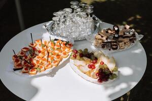 aire libre buffet mesa, emparedados en brochetas antes de el comienzo de el fiesta en contra el antecedentes de floración arboles en el jardín foto