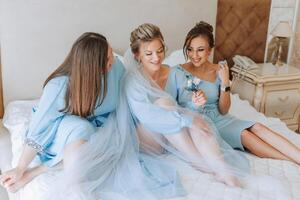 A beautiful bride and her bridesmaids are having fun in the morning. Wedding celebration. Happy girls at their best friend's wedding. A beautiful and elegant bride with her bridesmaids photo